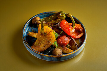 Grilled vegetables in a blue plate on a gold background