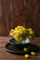 Gravy boat with ripe grapes on dark wooden background