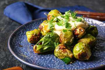 Plate with delicious roasted Brussels cabbage and sauce on table, closeup
