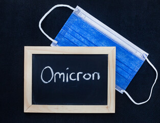 mask and Omicron written on blackboard on a black background