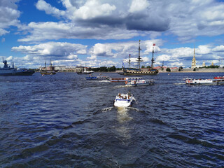 Fototapeta na wymiar Vacationing tourists on a yacht go to the Neva River to look at warships and sailboats for the Day of the Navy in St. Petersburg.