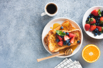 Sweet french toast with syrup and berries and cup of coffee on concrete table background, top view,...