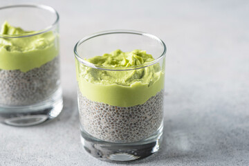 Chia pudding with avocado in a glass on grey background, closeup view. Healthy food