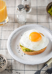 Toast with fried egg and avocado sauce on a plate, healthy breakfast meal concept