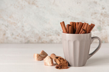 Cup with natural cinnamon sticks on table