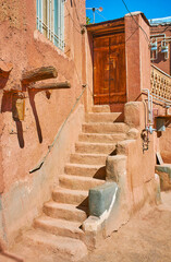 Adobe staircase leads to the house entrance with old wooden door, Abyaneh, Iran.