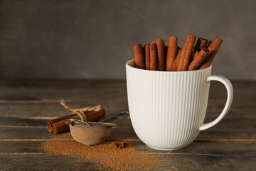 Cup with natural cinnamon sticks on table