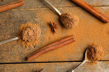 Composition with cinnamon sticks, powder and star anise on wooden background