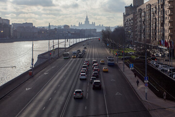 Cars stopped at a red traffic light. Car traffic at the road. Silhouette of Stalin's skyscraper. View from the Bogdan Khmelnitsky bridge. Berezhkovskaya embankment. Moscow, Russia.