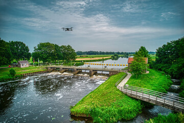 An aerial view with a flying drone in the background above a weir in the river Vecht. Lock keepers...