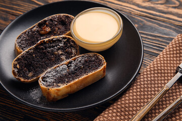 Plate with pieces of tasty poppy seed strudel on wooden background