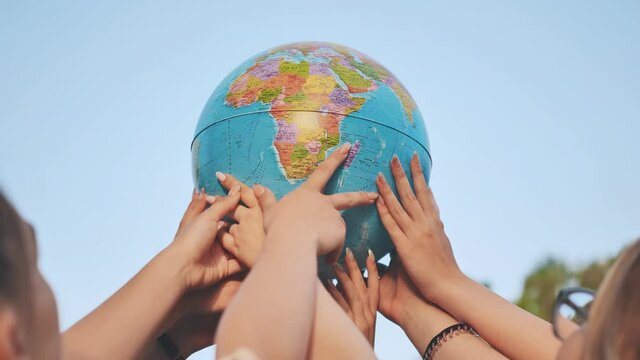 Friends hold the globe high above them.