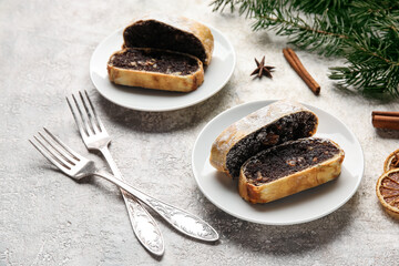Plates with pieces of tasty poppy seed strudel on light background