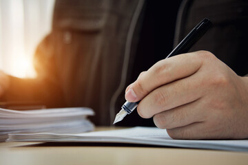Close up of businessman hand signing document with pen. Business concepts on investment contracts, agreements, and approvals, MOU.