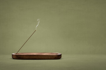 Smoking incense stick in a wooden holder - obrazy, fototapety, plakaty