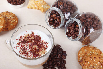 Still life with cappuccino with chocolate crumbs, cookies, crackers and coffee beans on table.