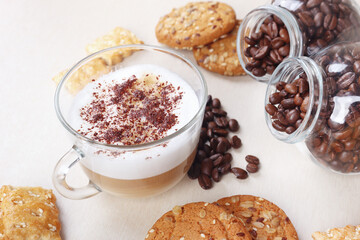 Breakfast with cappuccino with chocolate crumbs, cookies, crackers and coffee beans on table.