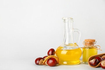 Bottle and decanter with essential oil and chestnuts on white background