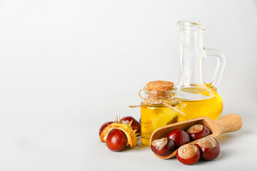 Bottle and decanter with essential oil and chestnuts on white background