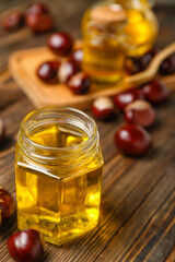 Jar of chestnut essential oil on wooden background, closeup