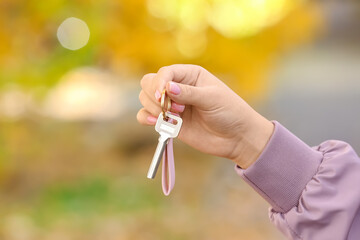 Woman holding key on chain outdoors