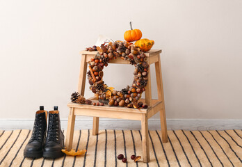Beautiful acorn wreath on step ladder and boots near light wall
