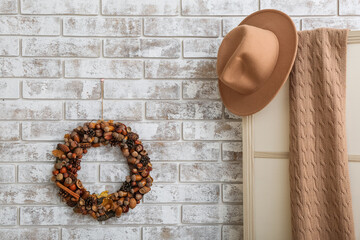 Beautiful acorn wreath on light brick wall and clothes in room