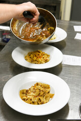 Crop cook serving freshly prepared Italian pasta in kitchen