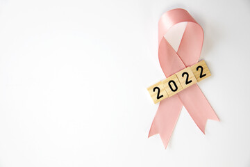 Pink ribbon with 2022 text isolated on white background, Cancer awareness, womans health, new year...