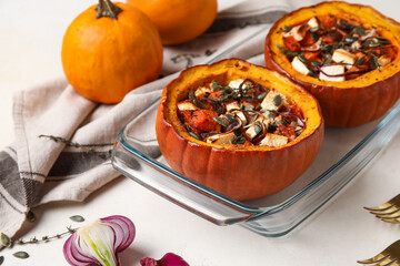 Baking dish with tasty stuffed pumpkins on light background