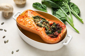 Baking dish with tasty stuffed pumpkin on light background