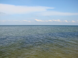 Panorama of the boundless wrinkled sea surface connecting with the blue cloudless sky on the horizon.
