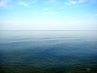 Fototapeta premium Panorama of the boundless wrinkled sea surface connecting with the blue cloudless sky on the horizon.