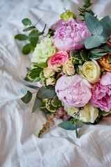 wedding bouquet with peonies lies on a white sheet