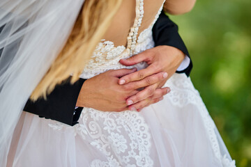 hugging hands behind back close-up at wedding white dress