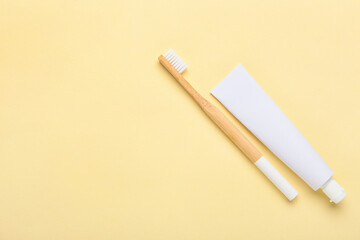 Wooden toothbrush and paste on color background