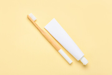 Wooden toothbrush and paste on color background