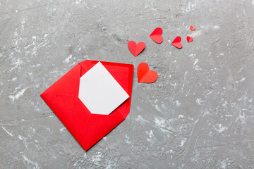 Red paper envelope with empty white card and heart on colored background. top view valentines day concept