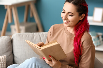 Naklejka premium Beautiful woman reading book on sofa at home