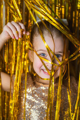Cute blonde toddler girl wearing fancy dress smiling against golden glitter background