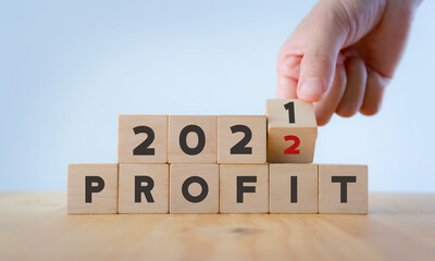 Business profit plan concept in 2022 . Build a profit and financial plan. Hand flip wooden cubes 2021 to 2022 with text 