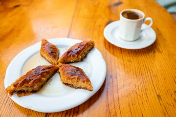 Coffee and sweet Turkish dessert baklava on a table in a rustic simple cafe