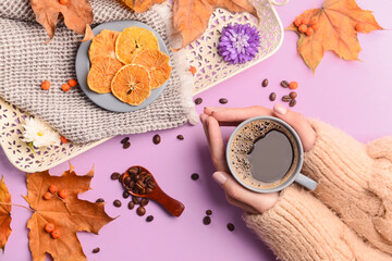 Fototapeta na wymiar Female hands with cup of coffee, beans, dried orange slices and leaves on color background, closeup