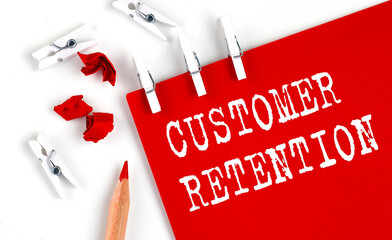 CUSTOMER RETENTION text on red paper with office tools on white background