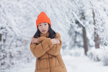 Lonely asian woman in winter park, sad and depressed, tired and frozen dressed in warm clothes