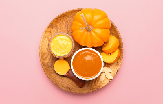 Plate with jars of natural mask and pumpkin on pink background