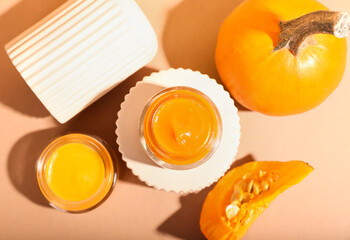 Composition with jars of natural mask and fresh pumpkin on color background, closeup