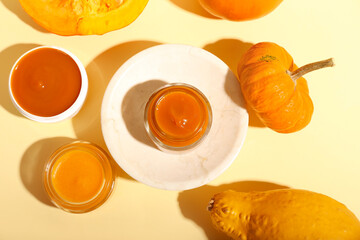 Jars of natural mask and pumpkins on color background