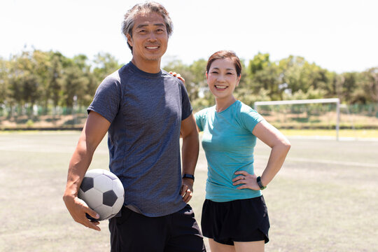 Happy mature couple playing football outdoors