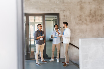 business, people and corporate concept - businessmen with name tags drinking coffee and water at office